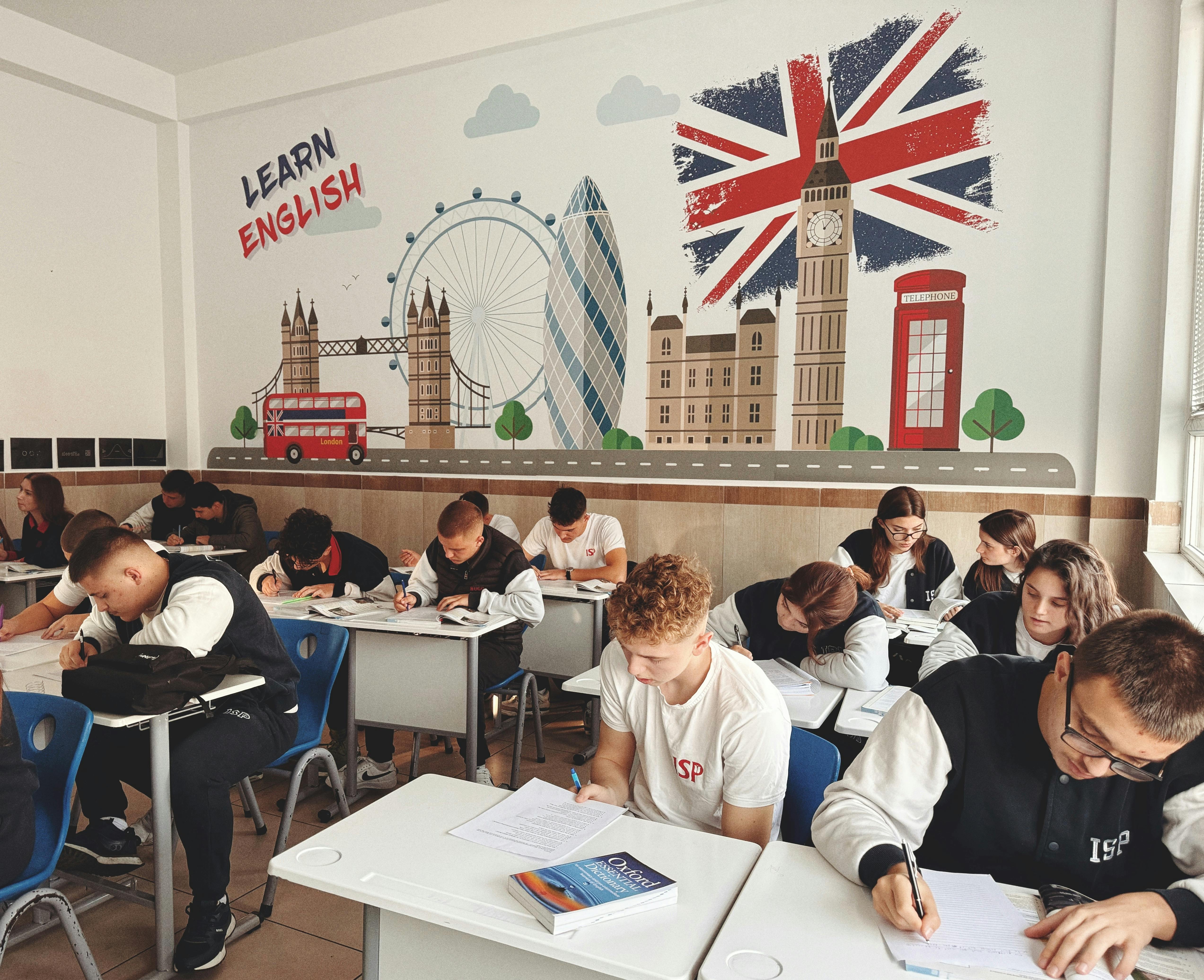 pexels-photo-29242202-29242202 Students studying English in a classroom with British themed decor and mural.